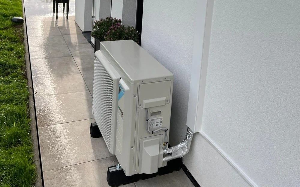 Fertig montiertes Außengerät an einer Hauswand, davor der Weg entlang der Terrasse.